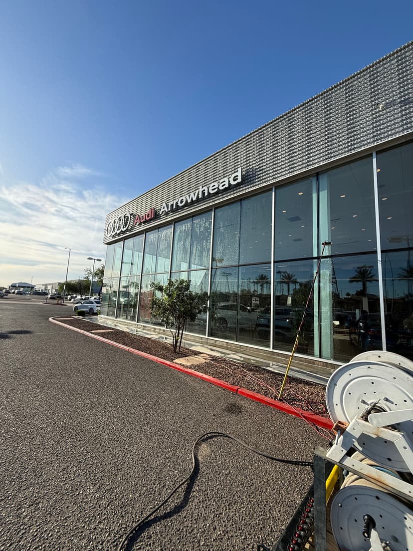 Audi Arrowhead dealership exterior with modern design and clear blue sky backdrop.