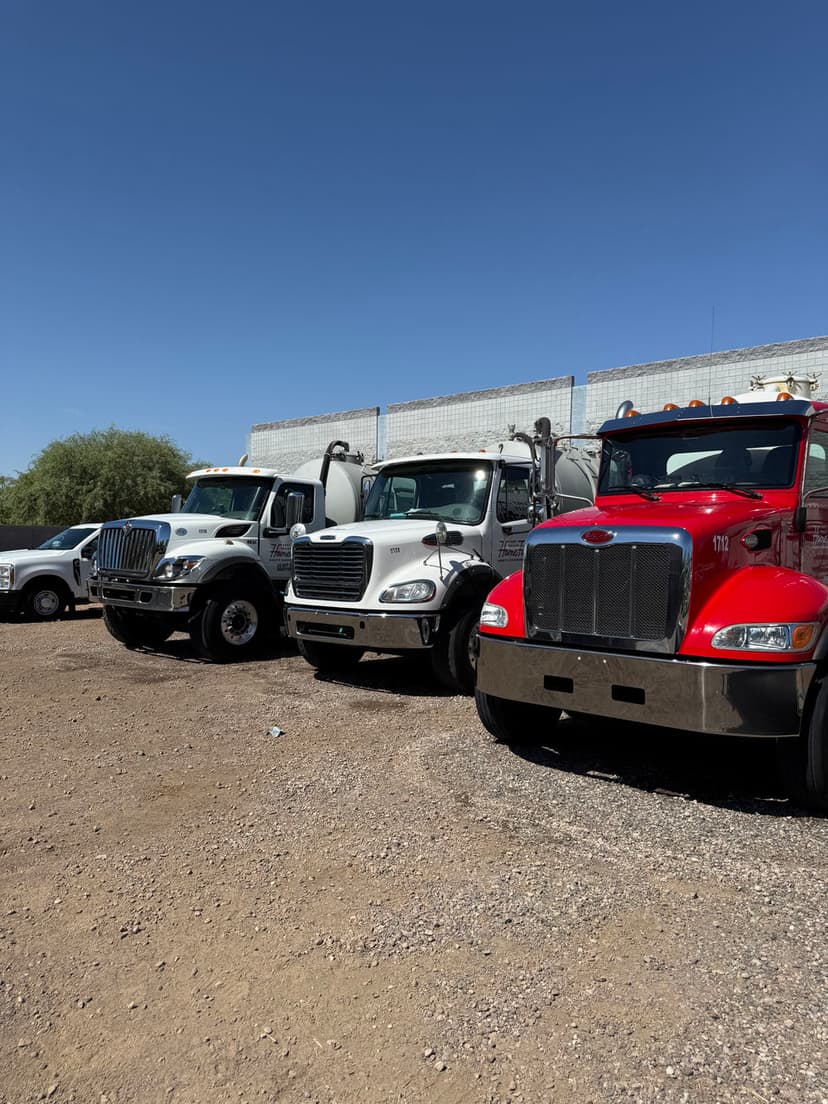 Lineup of various commercial trucks including white and red models in a sunny outdoor setting.
