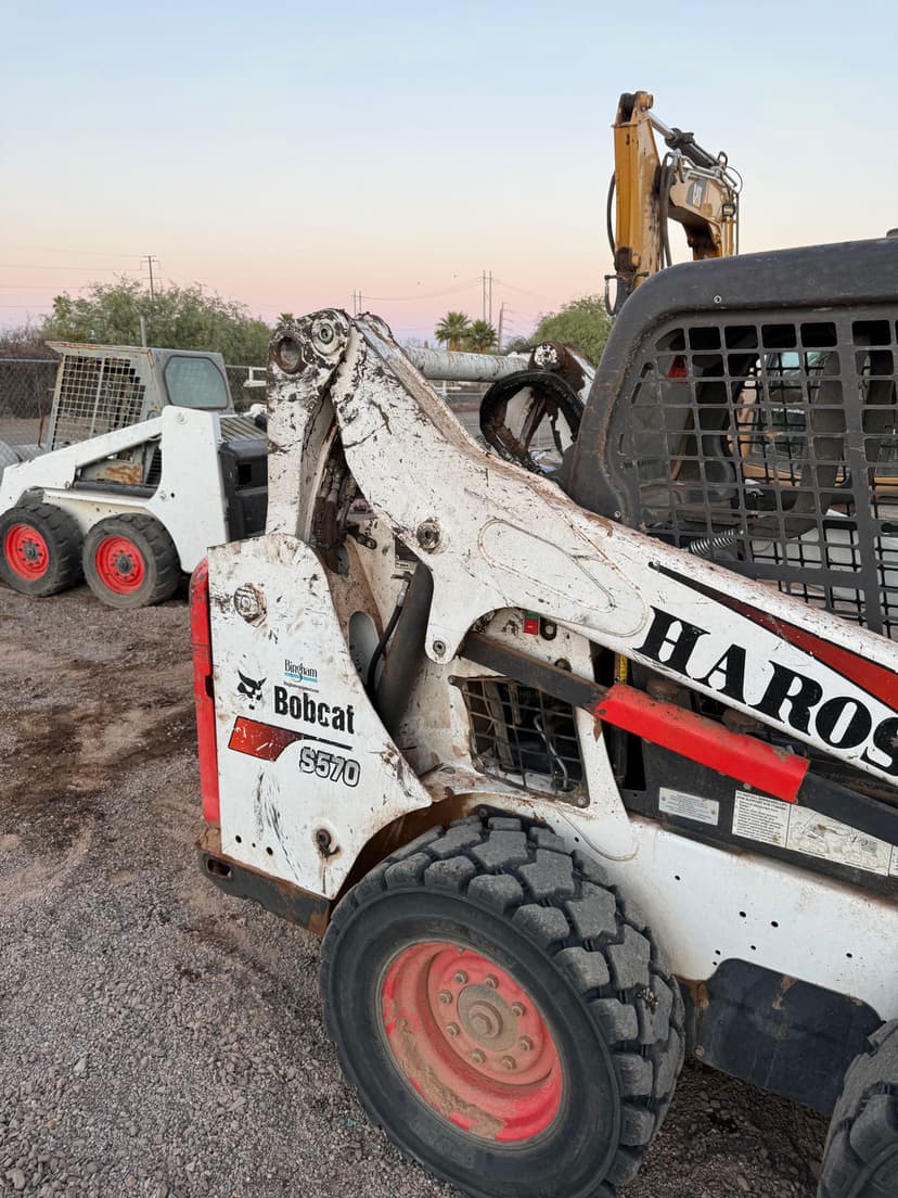 Bobcat S570 skid steer loader with dirty exterior parked at construction site at dusk.